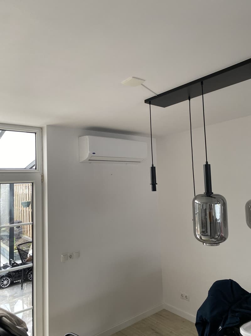 Wit wandmodel airco in een lichte woonkamer met hanglamp