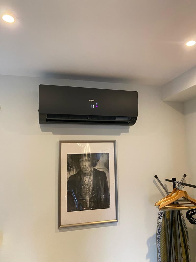Zwart wandmodel airco boven een ingelijste foto